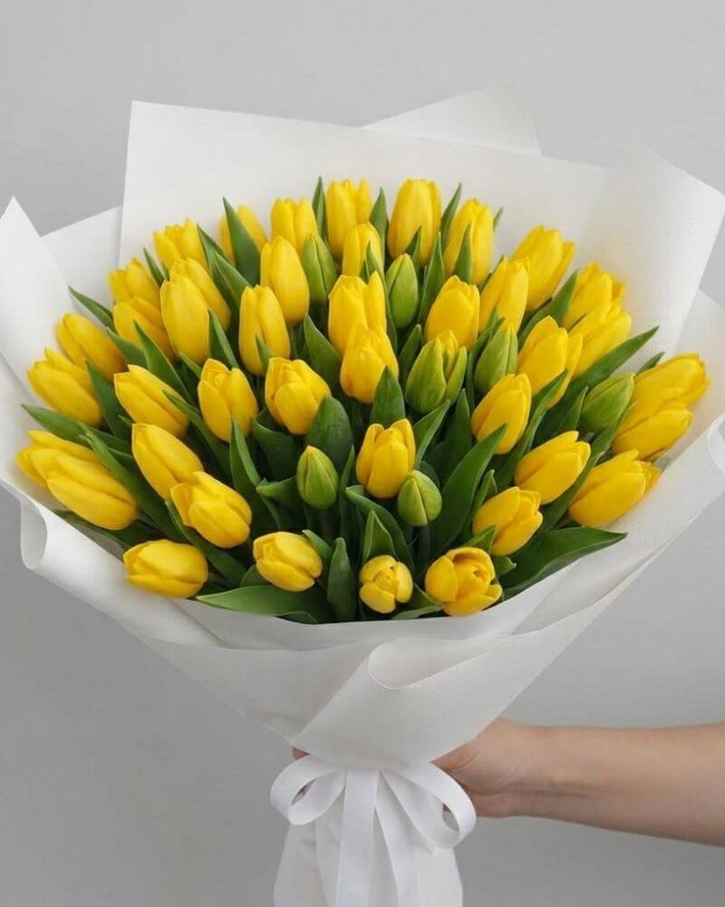 Bright yellow tulip bouquet wrapped in elegant white paper for luxury flower gifting in UAE
