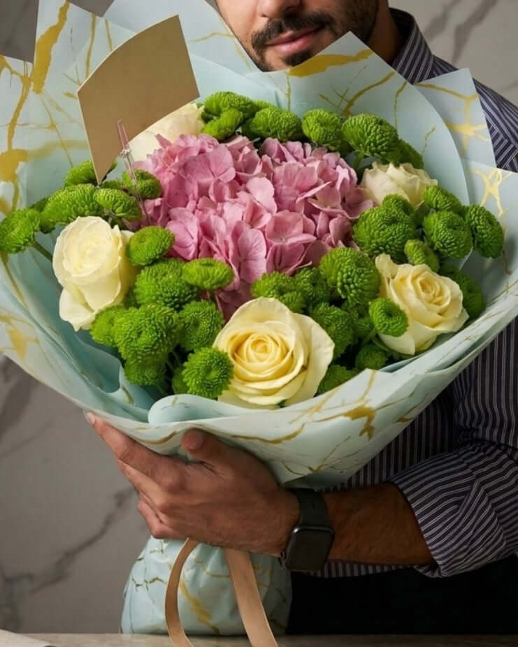 Elegant pastel mixed flower bouquet with pink hydrangea, ivory roses, and green chrysanthemums wrapped in luxury marble paper