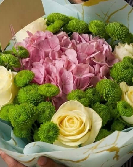 Elegant pastel mixed flower bouquet with pink hydrangea, ivory roses, and green chrysanthemums wrapped in luxury marble paper